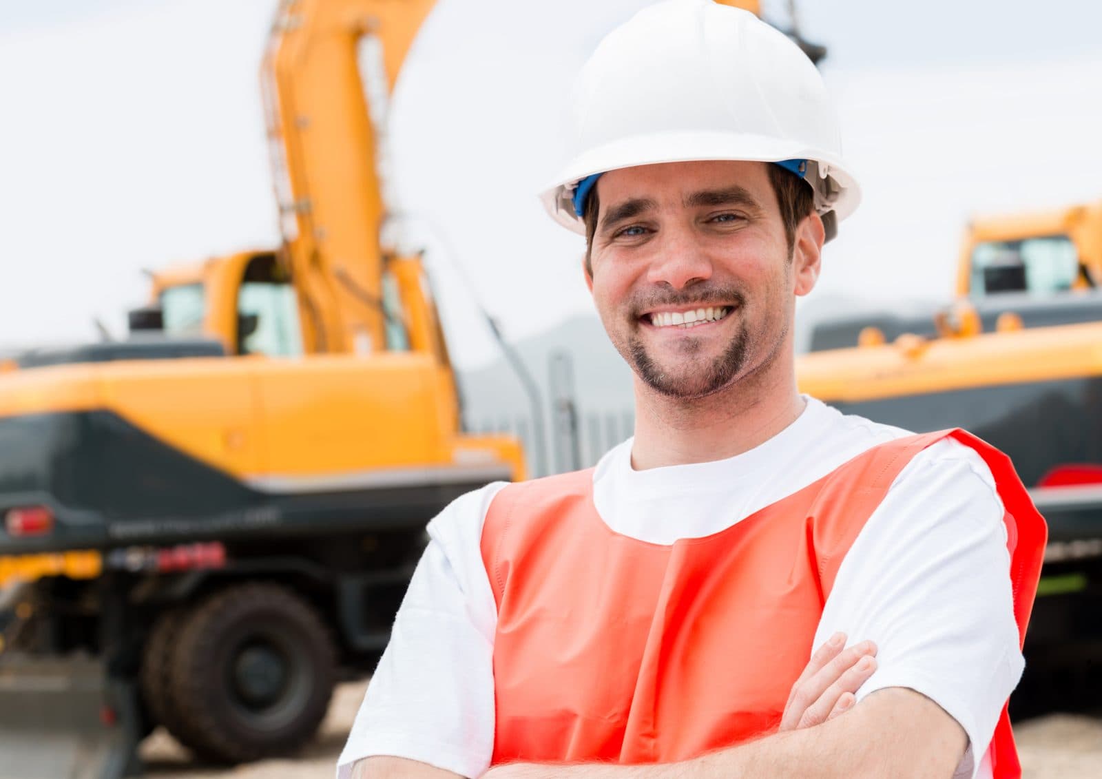 Smiling construction professional in a white hard hat and safety vest