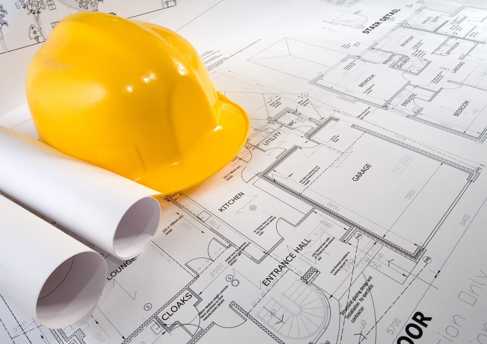 Yellow hard hat resting on rolled architectural floor plans