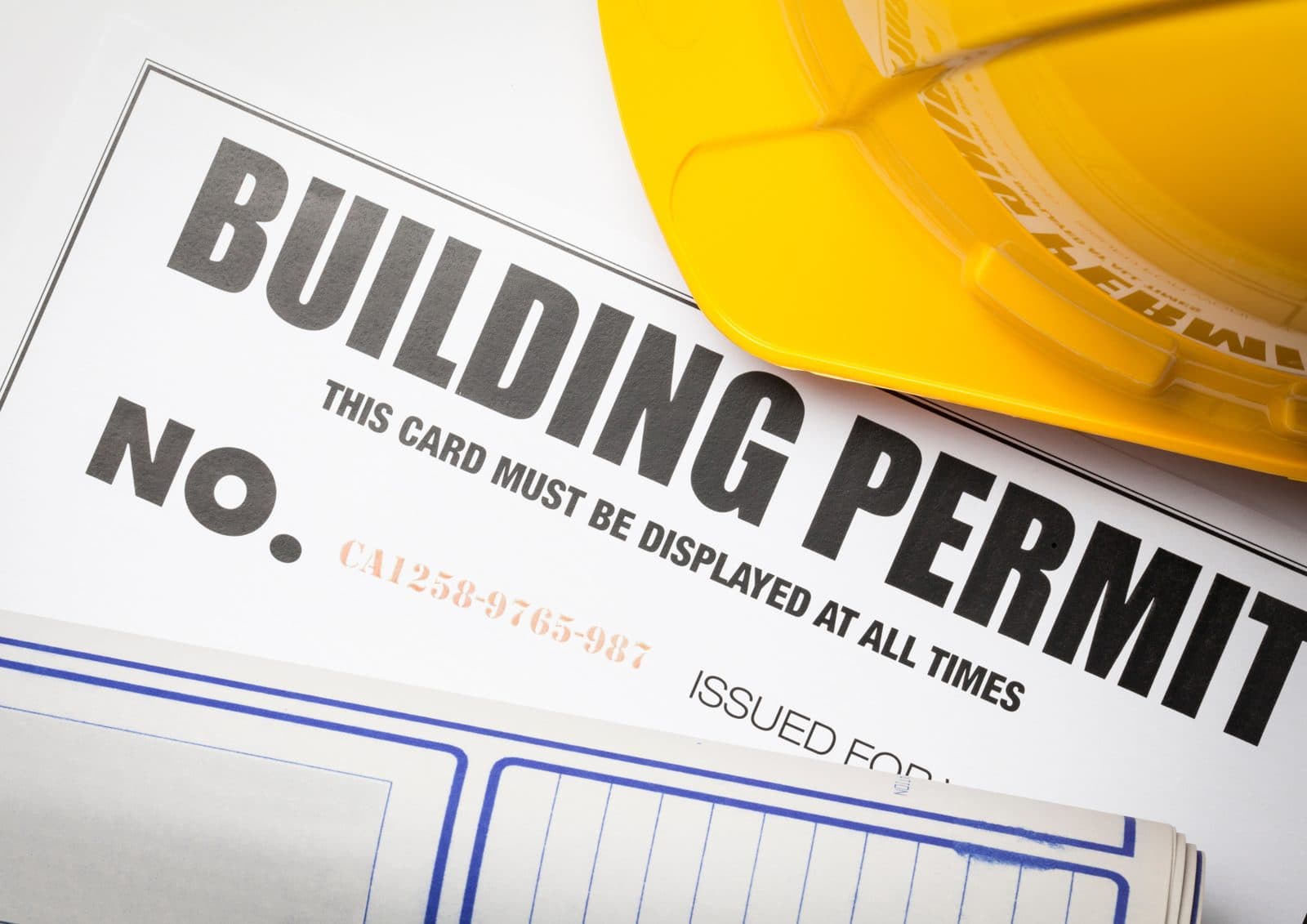 Building permit paperwork with a yellow hard hat