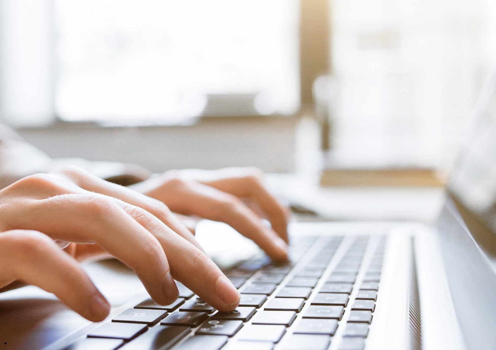 Hands typing on a laptop keyboard